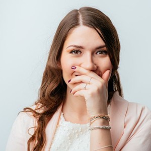 Smiling woman covering her mouth