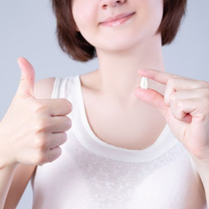 Woman holding her extracted tooth while making thumbs-up gesture