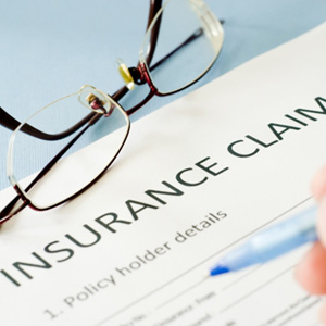 Person using pen to fill out insurance claim form