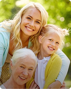 Three generations of women hugging outdoors