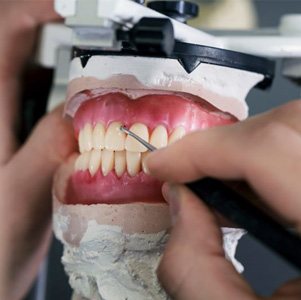 Hands of lab technician working on dentures