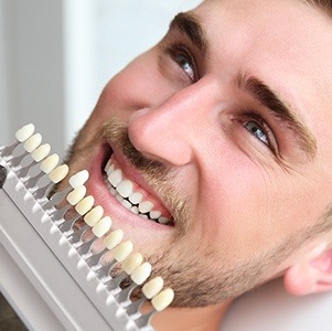 man checking smile against veneer chart