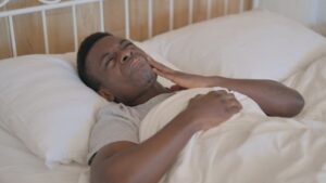 Man lying in bed, suffering from a toothache 