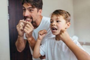 Father and son flossing their teeth