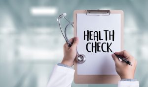 “Health check” written on clipboard held in doctor’s hands