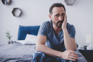 Man sitting up in bed, suffering from toothache