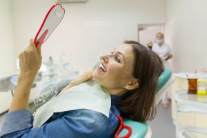 Patient smiling in mirror after receiving veneers or crowns