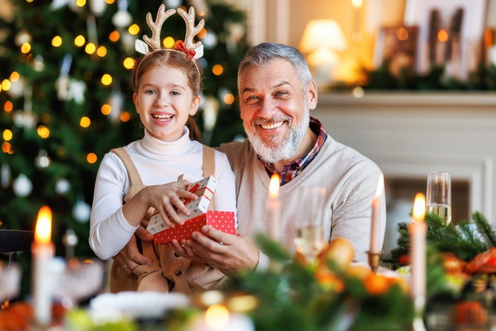 Grandfather and granddaughter smiling while exchanging presents