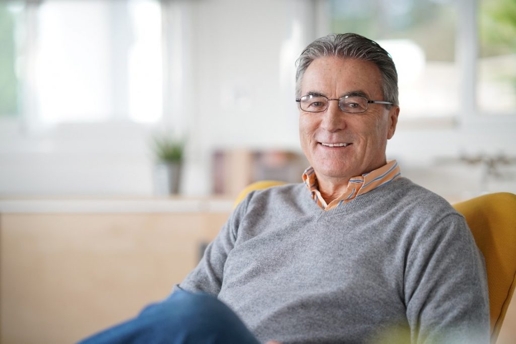 Senior man with dentures smiling at home