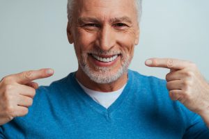 Smiling senior man pointing at his dentures