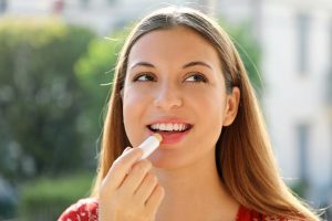 Woman applying lip balm to protect her lips from the sun