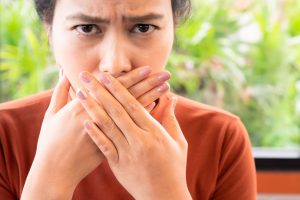 Woman covering her lips, concerned about white film in mouth