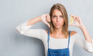 Woman giving thumbs down to lemons, which can cause a dental emergency