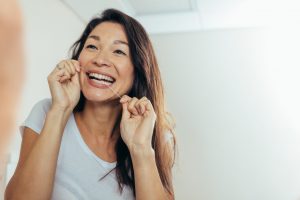 Woman using dental floss to clean between her front teeth