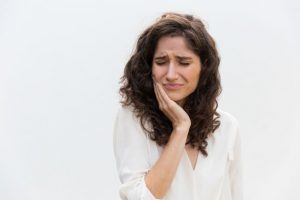 Woman with a tooth infection standing against white background