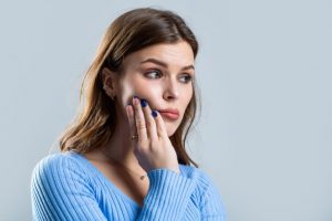 Woman with hand on mouth, concerned about swollen gums