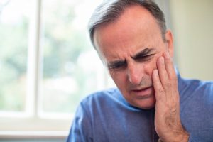 middle-aged man in blue shirt suffering toothache pain