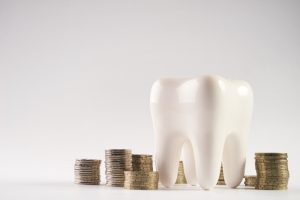 tooth model next to stacked coins against light background