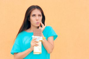 woman with chocolate bar and tooth pain